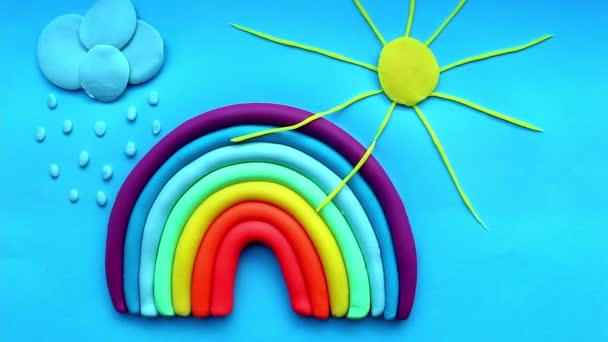 青い背景にはカラフルな虹 太陽とプラスチックの雲 空と太陽 プラスチック製 — ストック動画