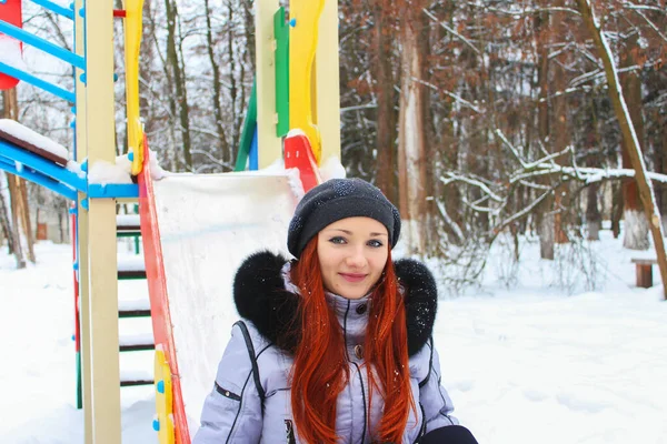 Genç bir kadın kışın parkta eğleniyor.