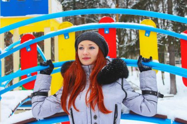 Genç bir kadın kışın parkta eğleniyor..