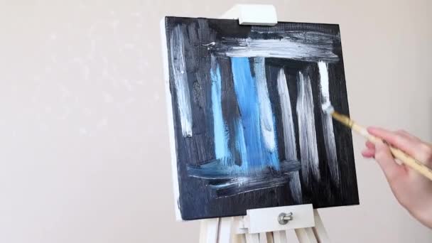 女性の手は筆を持ち 油絵具で絵を描く 黒と青の色合いのキャンバスに絵を描く — ストック動画