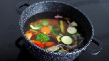 Vegetables are boiled in a casserole. Vegetables spin around in a pot with hot water. The concept of vegetarianism and healthy organic food.
