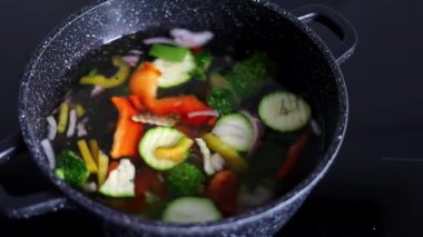 Vegetables are boiled in a casserole. Vegetables spin around in a pot with hot water. Slow-motion. The concept of vegetarianism and healthy organic food