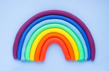 Colorful rainbow of plasticine on blue background. Made from plasticine. Isolate.