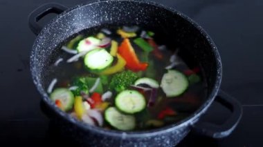 Vegetables are boiled in a casserole. Vegetables spin around in a pot with hot water. The concept of vegetarianism and healthy organic food