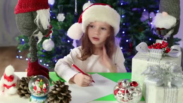 Little Girl Red Santa Hat Writes Letter Santa Claus Her — стоковое видео