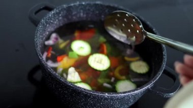 Vegetables are boiled in a casserole. Vegetables spin around in a pot with hot water. Slow-motion. The concept of vegetarianism and healthy organic food.