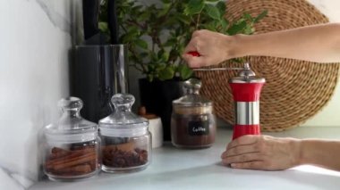 Kadın elleri, modern bir mutfağın arka planında kahve çekirdeklerini öğütüyor. Kendi kahveni öğütüyorsun. 4K görüntü.