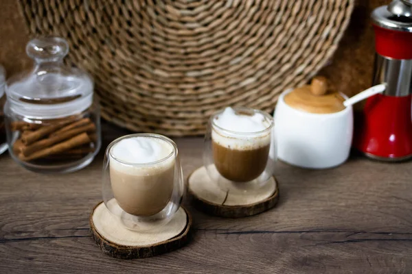 Two glass cups of coffee with foam on a wooden background. Breakfast coffee concept. Process of making coffee at home.