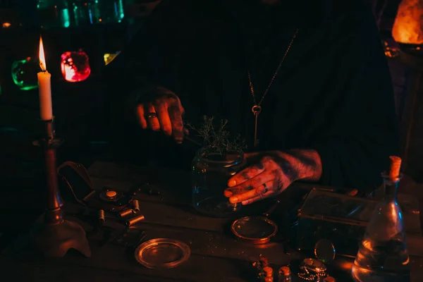 Le mani di stregone alchimista preparano un veleno di pozione magico con erbe in fiaschetta a tavola — Foto Stock