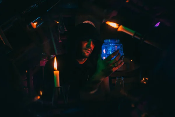 炼金术士手里拿着一瓶魔药在可怕的车间里万圣节期间的巫师魔术师 — 图库照片