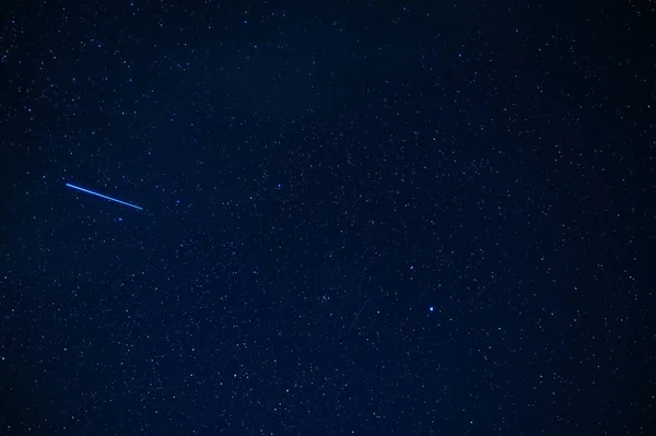 shooting star meteorite comet on background of blue dark starry sky with galaxies and nebulae