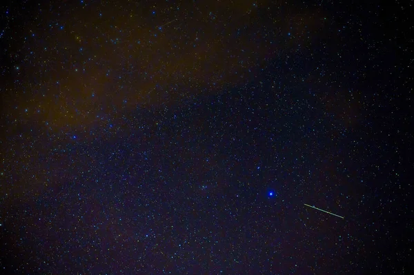 shooting star meteorite comet on background of blue dark starry sky with galaxies and nebulae