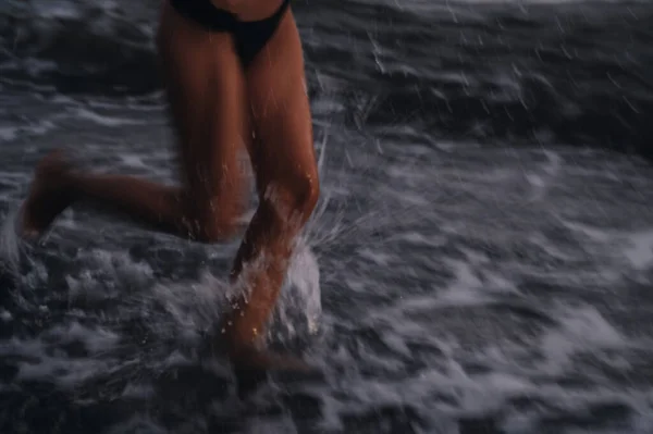 Ноги дівчини в купальнику, що біжить уздовж берега на пляжі біля моря — стокове фото