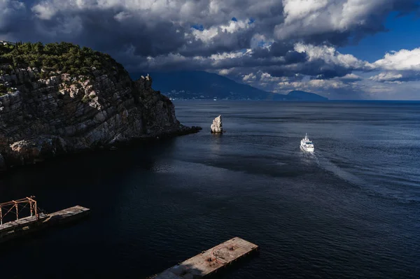 Білий круїзний корабель з туристами вітрила на морі біля скель в похмурий літній день — стокове фото