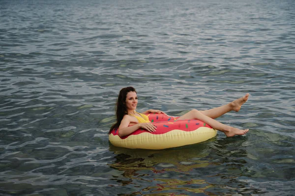 Esbelta chica nada en un círculo inflable en el mar en verano — Foto de Stock