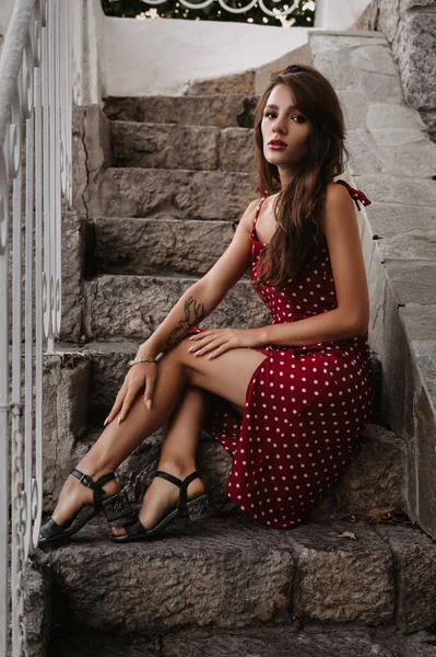 Attraente ragazza bruna con figura sexy posa su una scala di pietra sui gradini — Foto Stock