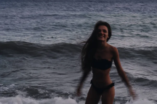 Счастливая девушка в купальнике наслаждается свободой на пляже у моря с волнами — стоковое фото