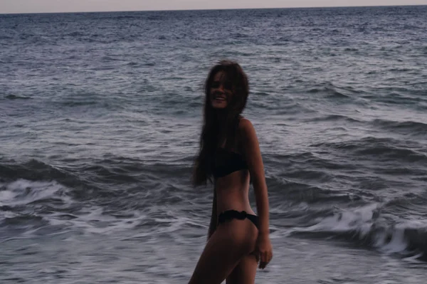 Счастливая девушка в купальнике наслаждается свободой на пляже у моря с волнами — стоковое фото