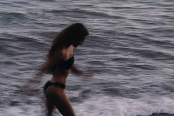 Menina feliz em um maiô corre feliz e liberdade na praia junto ao mar com ondas — Fotografia de Stock
