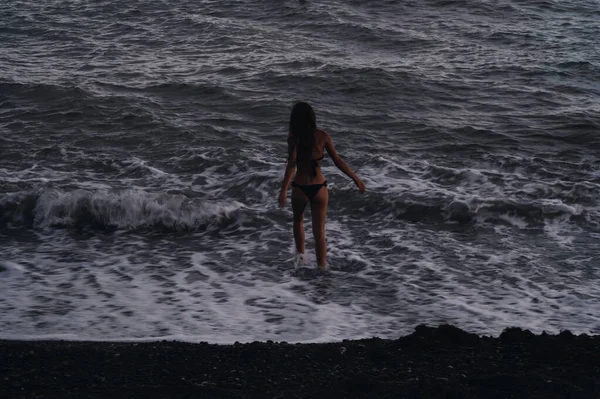 Счастливая молодая девушка с сексуальной добычей в купальнике приходит купаться в море с волнами — стоковое фото