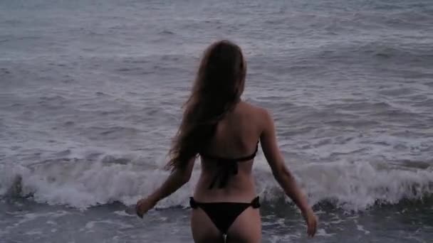 Sexy dziewczyna w strój kąpielowy stoi z jej plecami i prostuje jej włosy na wietrze na plaży — Wideo stockowe