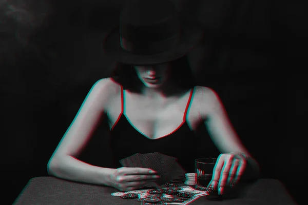 Žena v klobouku hraje poker u stolu s kartami a žetony v kasinu — Stock fotografie