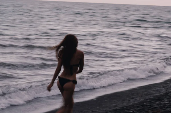 Šťastná dívka v plavkách šťastně běží a svoboda na pláži u moře s vlnami — Stock fotografie
