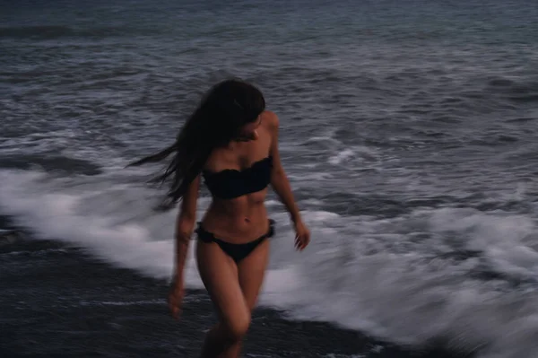 Счастливая молодая девушка в купальнике наслаждается свободой и жизнью на пляже у моря — стоковое фото
