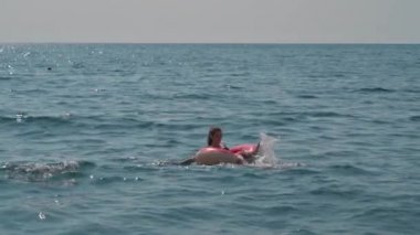 Mayolu genç bir kadın denizde şişirilebilir bir dairede yüzüyor.