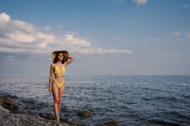 girl in a straw hat on the beach at the sea in summer