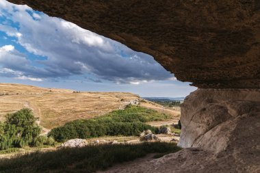 View from a cave in mountains to blue sky on sunny summer day