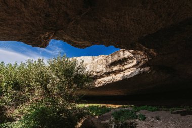 View from a cave in mountains to blue sky on sunny summer day