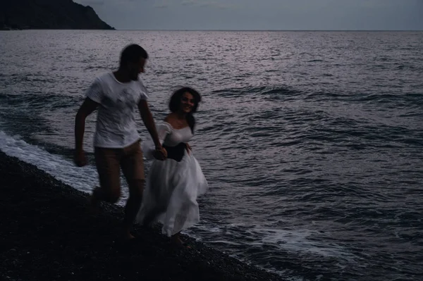 Birbirine aşık çiftler deniz kenarında el ele koşuşturuyorlar.