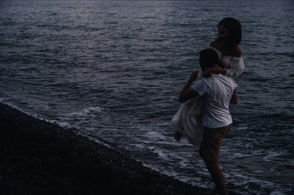 Aşık bir adam kız arkadaşını sahilde sırtında taşır.