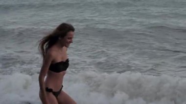 happy girl in a swimsuit runs along the beach to the sea in the summer