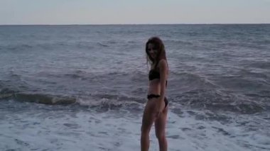 young sexy girl in swimsuit joy, smiles and enjoys on beach by sea in summer