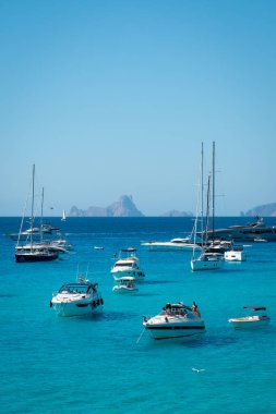Arka planda Es Vedra ile Cala Saona 'da demirlemiş tekneler.