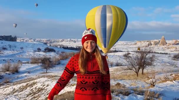 Krásná pozitivní dívka mává rukou na kameru na pozadí létajících balónů. — Stock video