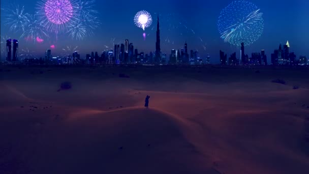 AERIAL. Young woman in traditional arabian dreess - abaya stands on the mounting at the desert and looks on the fantastic fireworks show at the modern Dubai city. — Wideo stockowe