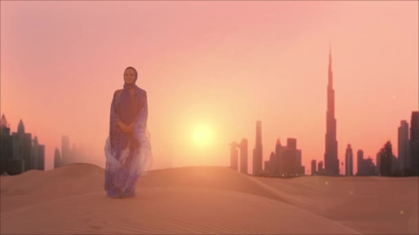 Woman in traditional arab dress stands on the deserts mountains. Dubai city silhouette on the background — Αρχείο Βίντεο