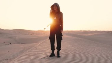 Woman stands in the desert at sunset. High quality 4k footage