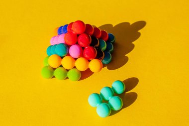 Tek parçalı piramit, sarı arkaplanda gölgesi olan çok renkli parlak plastik parçalardan düştü.