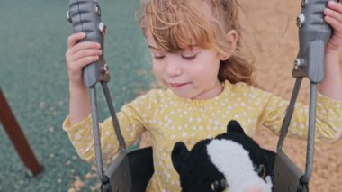 Güzel küçük kız. Oyuncak kedisiyle sallanan bebek salıncakta.
