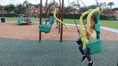 Küçük kızın çocuk parkında salıncakta sallanması.