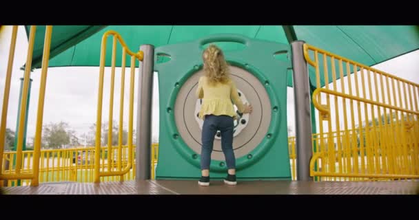 Kislány játszik forgó érzékszervi játék a játszótéren — Stock videók