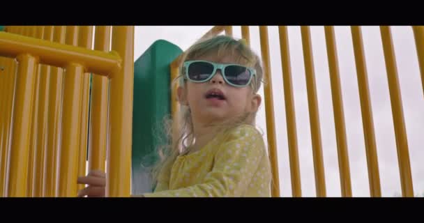 Meisje met zonnebril op speelplaats — Stockvideo