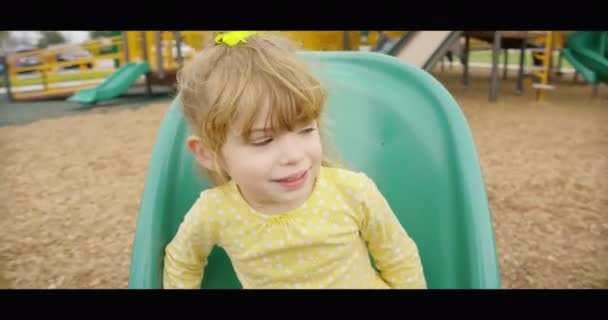 Close-up dari gadis kecil yang cantik menikmati berputar-putar di taman bermain — Stok Video
