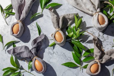 Paskalya tavşanı yumurtaları ve çarşaf peçeteli Paskalya bayramı arkaplanı. Paskalya dekorasyonu, üst manzara. Boşluğu kopyala.