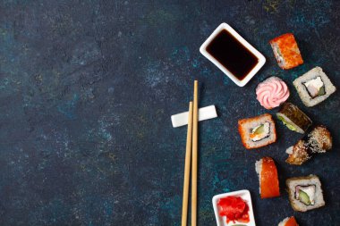 Çubuklu suşi seti ve mavi arka planda soya sosu. Boşluğu kopyala, üst görünüm.