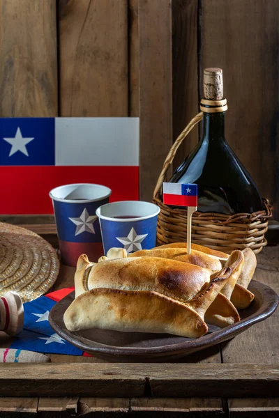 Şili 'nin bağımsızlık günü kavramı. fiestas patrias. Tipik pişmiş empanadas de pino, şarap ya da chicha, şapka ve emboque. 18 Eylül partisinde yemek ve içki, ahşap arka plan.